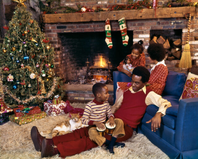 Parents and their two children sitting in front of a fire