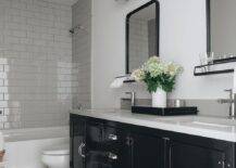 Restoration Hardware Pharmacy Double Vanity featuring a light gray quartz countertop, chrome fauces and a black mirror with a shelf. Gray and black diamond pattern floor tiles bring a charming finish to the surface of the bathroom.