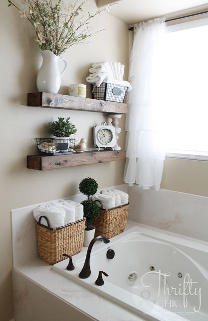 Chic bathroom with floating shelves that hold a clock, towels, and a metal wire basket.