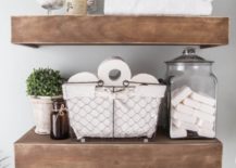 Two thick floating shelves made of wood carrying toiletry, soap, and towels.