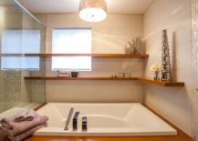 Chic bathroom boasting floating shelves that hold towels and art pieces.