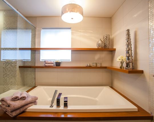 Chic bathroom boasting floating shelves that hold towels and art pieces.