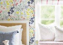 Bedroom features a cane headboard with gingham pillow on floral wallpaper and a red and white window shade.