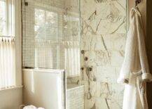 Marble grid walk in shower features gray marble offset floor tiles, a marble slab shower bench and clear shower partition.