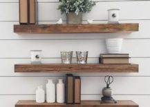 Three floating shelves, holding a plant, books, and small buckets.