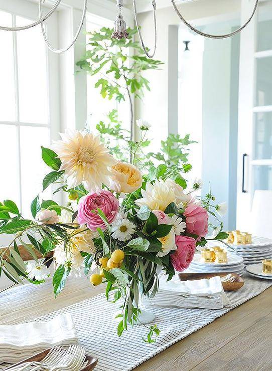 Rustic oak plank top dining table styled with a striped runner and lovely florals in a transitional dining room design.