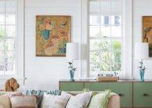 A tan sectional accented with tan and green pillows sits on a green and white diamond pattern rug.