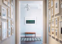 Hallway gallery with framed pictures on both walls, while a leather bench is at the end of the hall.