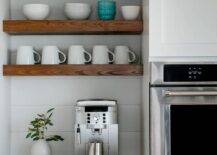 Kitchen features a coffee station under rustic wooden shelves on a white shiplap backsplash.