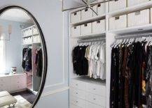 White and blue custom walk in closet features a full length oval mirror, white built in drawers and white woven baskets on upper shelves.