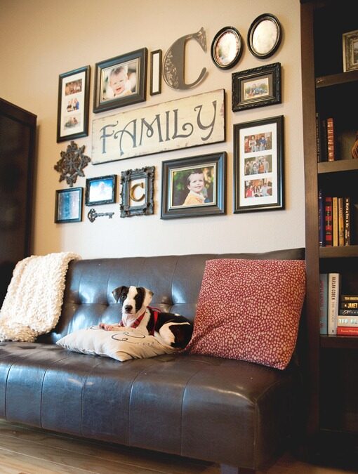 Picture gallery in the living room, centered is a big "Family" picture fronted by a dog sitting on a coach.