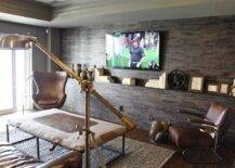 Parade of Homes - Media room with floor to ceiling stone accent wall accented with flatscreen TV and whatnots. Media room features Restoration Hardware 1950s Copenhagen Chair and brown leather chair paired with fabric covered coffee table over jute rug.