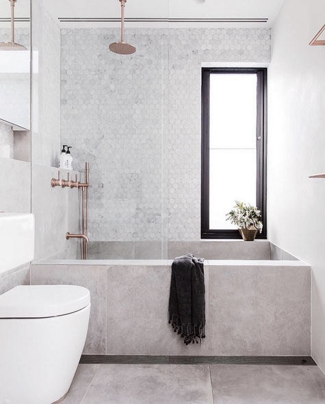 A bathroom featuring a marble-like tub and copper fixtures, creating a contrasting color scheme.