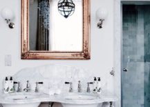 Marble double vanity flanked by a mirror with a copper frame.