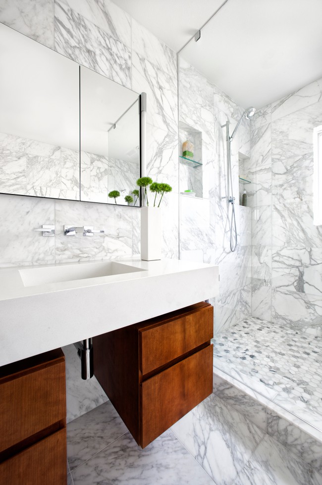 A luxurious bathroom featuring elegant marble walls and flooring with wood cabinets.