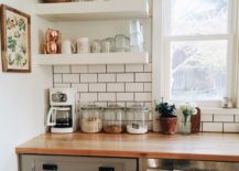 Minimalist kitchen that has floating white shelves to hold mugs, cups, and wine glasses.