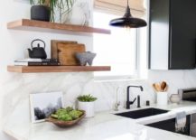 Minimalist kitchen with L-shaped countertop and wooden floating shelves.