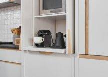 White drawers accented with blond oak hardware are stacked beneath a coffee station boasting white folding doors and pull out shelves.