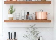 Rustic kitchen with floating shelves that stocks glassware, pots, and jam.