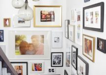 Corner stairway with lots of framed pictures and lamps.