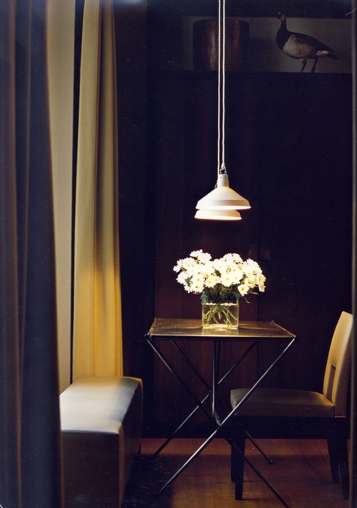 A wooden table with a vase of white flowers in the center is surrounded by two chairs.