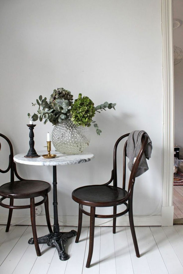 A minimalist room with a white-top table and two black chairs. The chairs are positioned on either side of the table, creating a symmetrical look.