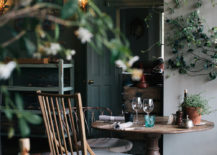 A table sits in the center of the image, adorned with two chairs near each other surrounded by greenery.