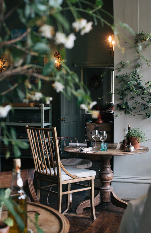 A table sits in the center of the image, adorned with two chairs near each other surrounded by greenery.