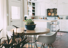 A dining room with a table, two chairs, carpet, and chandelier.