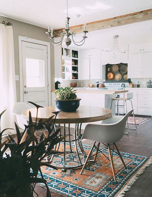 A dining room with a table, two chairs, carpet, and chandelier.