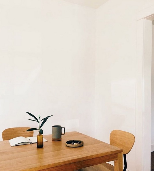 A wooden table is placed in the center, accompanied by two matching chairs.