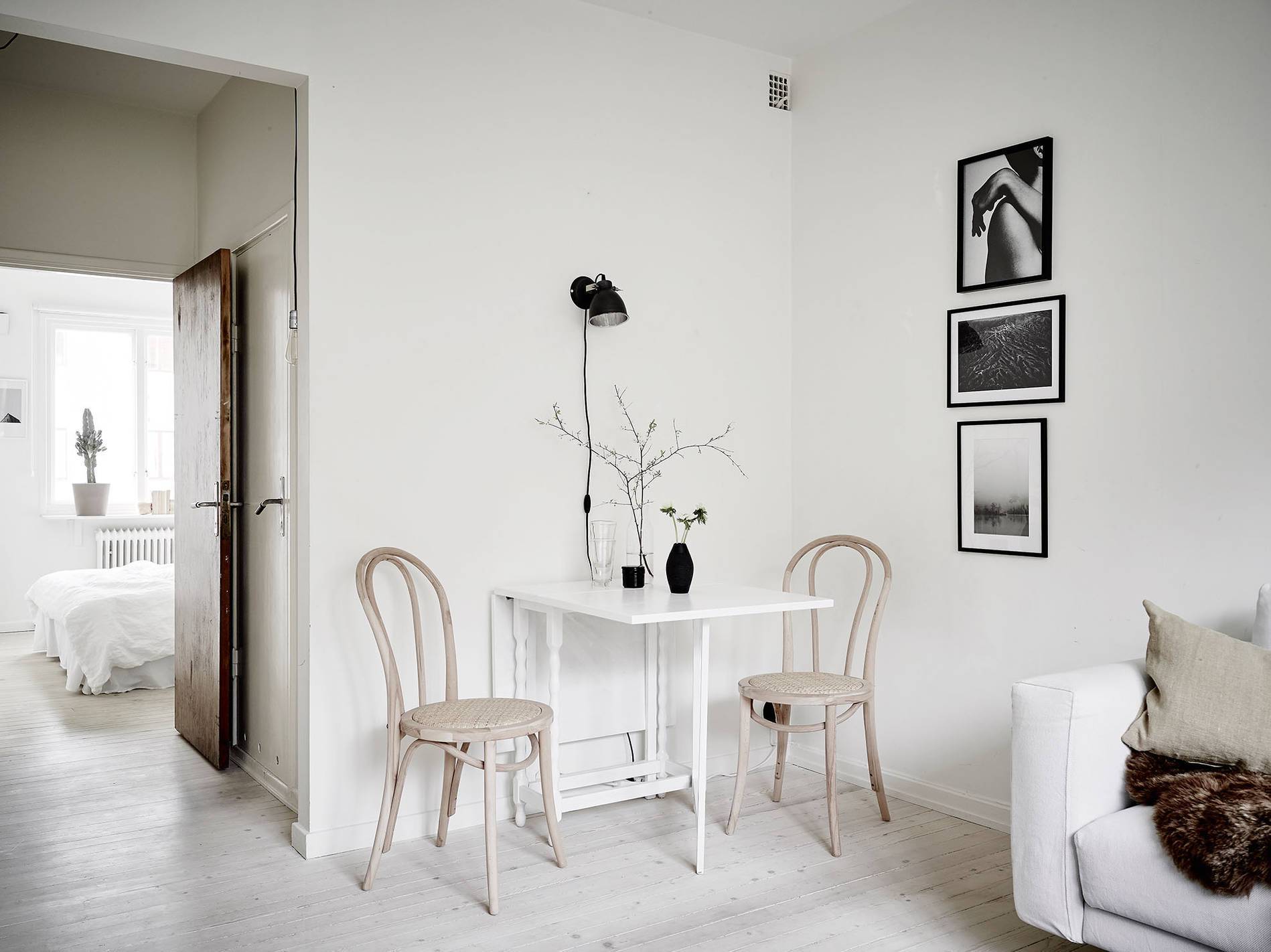 A minimalist white room with a wooden table and two chairs.