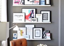 A leather chair flanked by three white floating shelves displaying art pieces.