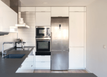 A modern kitchen with black countertops and white cabinets.