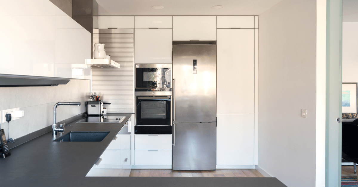 A modern kitchen with black countertops and white cabinets.