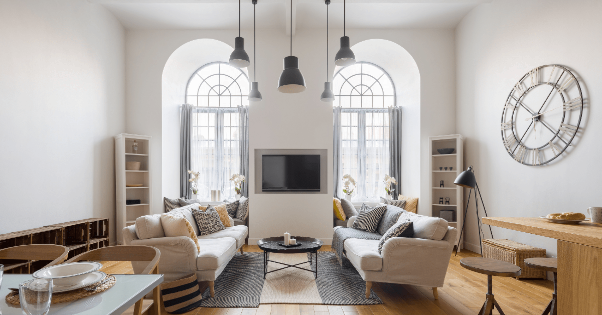 A living room dining room combo with two large ceiling to floor windows.