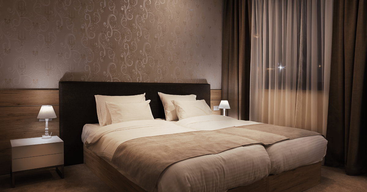 A chic bedroom with white pillows and beige throw blanket.