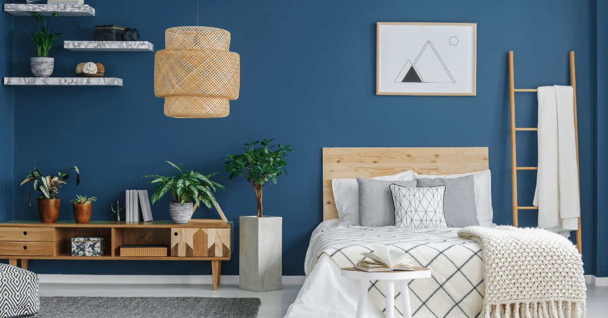 A bedroom with blue wall and white bedding.