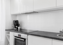 A white modern kitchen with black countertops.