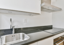 White cabinets with black kitchen countertops.