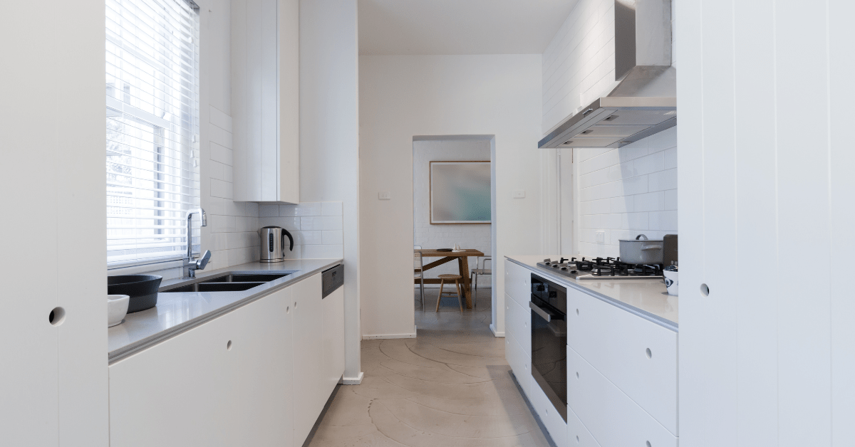 White galley kitchen with light hardwood flooring.