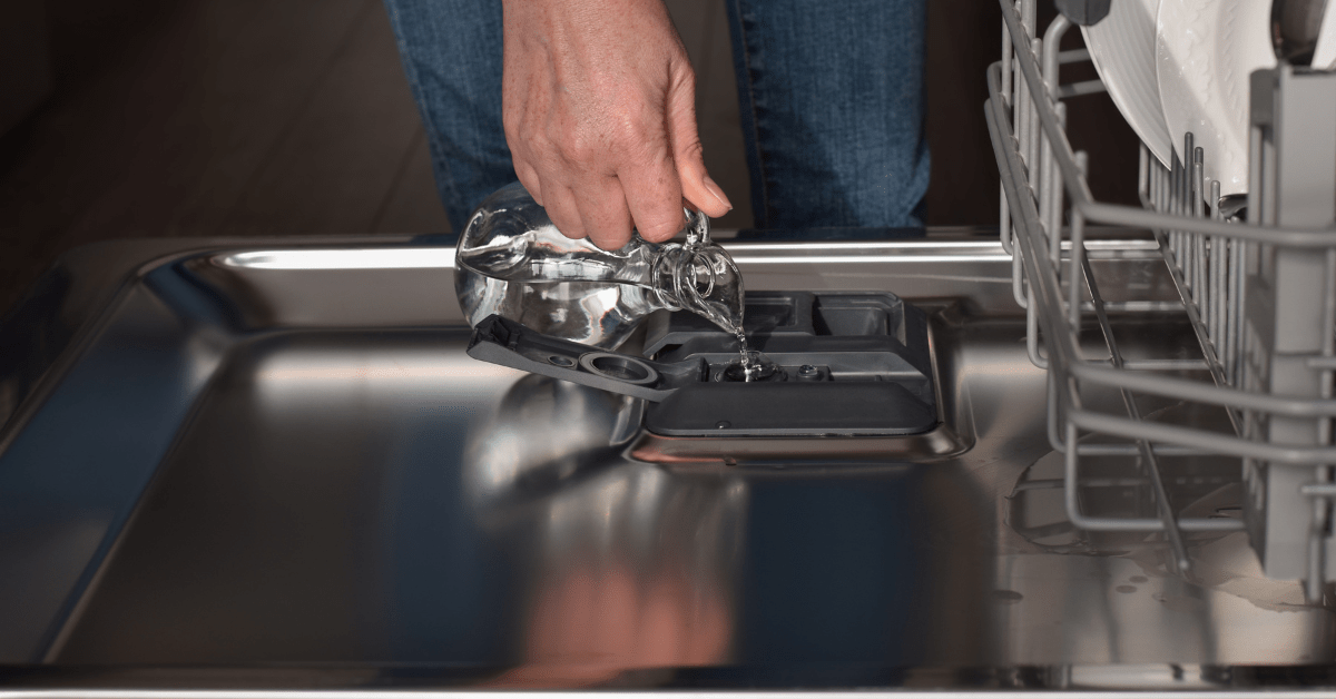 Pouring vinegar into a dishwasher to clean it.