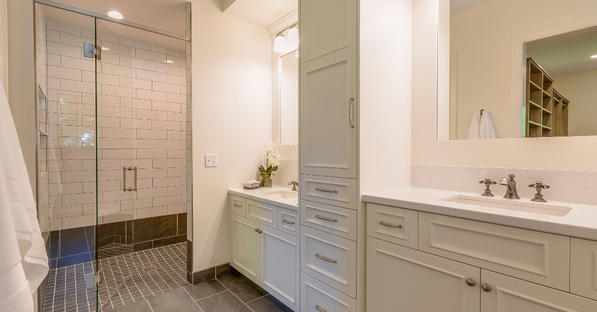 White subway tile shower with black floor tiles and glass door.