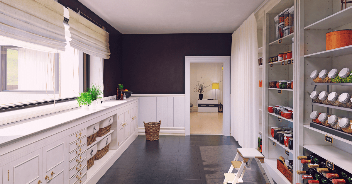 Walk in pantry with blue walls and white drawers.